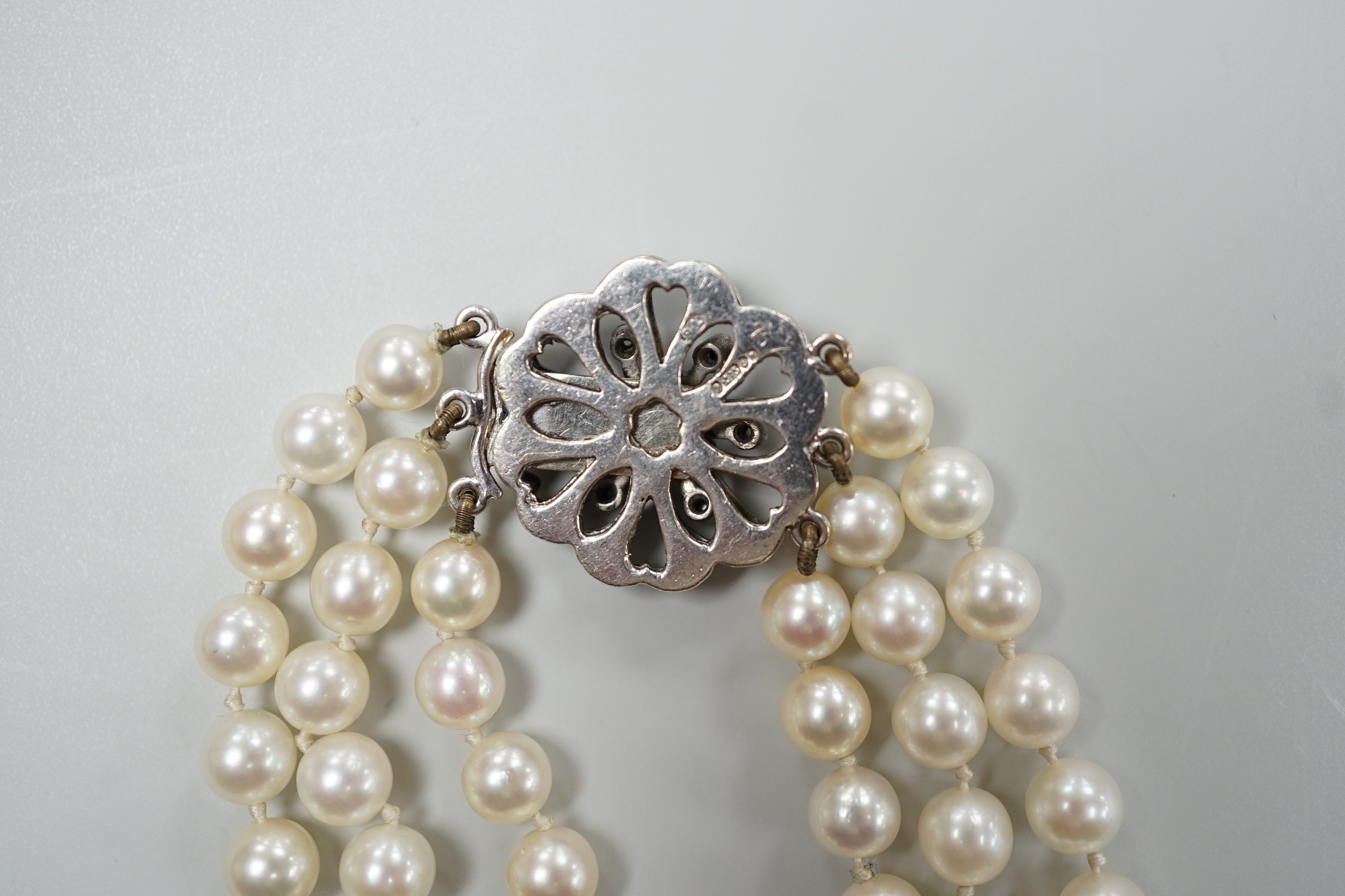 A 1960's triple strand cultured pearl bracelet, with 9ct white gold and diamond chip set clasp, 20cm.